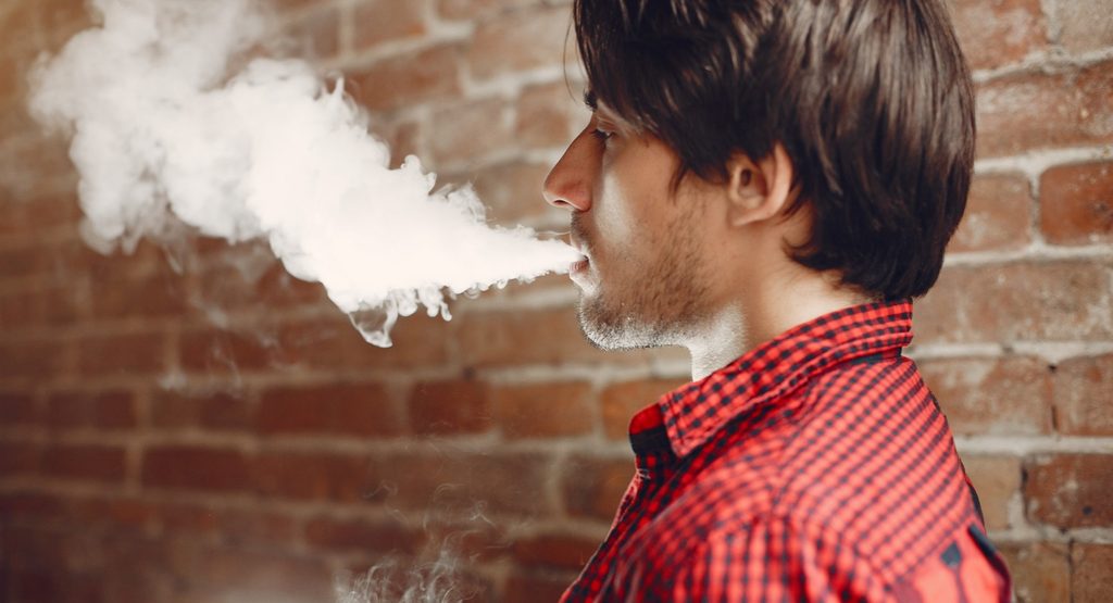 Person using an electronic cigarette and inhaling vape aerosol
